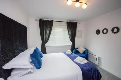a bedroom with a bed with blue and white pillows at Modern 3 Bed Flat Balloch in Jamestown
