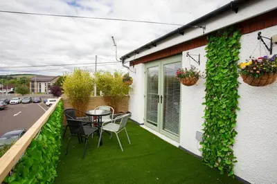 a balcony with a table and chairs on the side of a house at Modern 3 Bed Flat Balloch in Jamestown