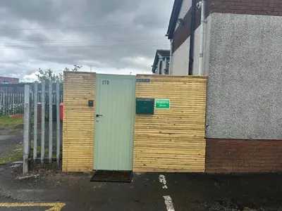 a wooden wall with a door next to a building at Modern 3 Bed Flat Balloch in Jamestown