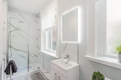 a white bathroom with a sink and a shower at Spacious City Apt - Dunfermline in Fife