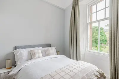 a white bedroom with a bed and a window at Spacious City Apt - Dunfermline in Fife