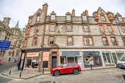 a red car parked in front of a building at Spacious City Apt - Dunfermline in Fife
