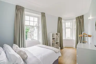 a white bedroom with a bed and a window at Spacious City Apt - Dunfermline in Fife