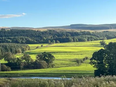 a view of a green field with a river at Ryehill with Fishing in Sanquhar
