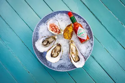 a plate of oysters and a bottle of hot sauce at The Pierhouse Hotel in Port Appin