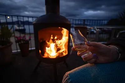 a person holding a glass of wine in front of a fire at The Pierhouse Hotel in Port Appin