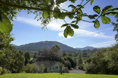 a house in a field with mountains in the background at Bruach in Balquhidder