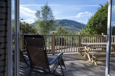 a chair and a table on a porch with a view at Bruach in Balquhidder