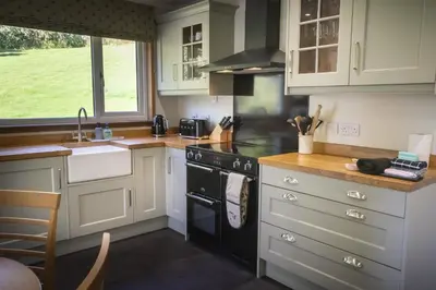 a kitchen with white cabinets and a black stove top oven at Bruach in Balquhidder