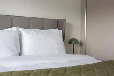 a bed with white pillows and a green lamp at Penthouse Apartment at Loch Lomond with 2 bedrooms in Balloch