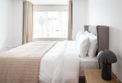 a white bed with white pillows and a window at Penthouse Apartment at Loch Lomond with 2 bedrooms in Balloch