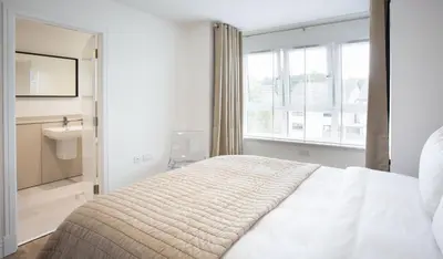 a white bedroom with a bed and a window at Penthouse Apartment at Loch Lomond with 2 bedrooms in Balloch