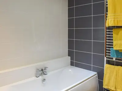 a bathroom with a white tub and yellow towels at Wallace View in Stirling
