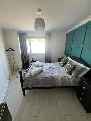a bedroom with a large bed with a blue headboard at Elro House Holiday Let in Tillicoultry