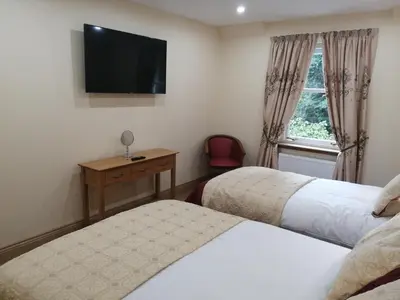 a bedroom with two beds and a television on the wall at Cumberland Hotel in Edinburgh