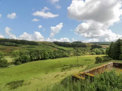 a green field with trees and clouds in the sky at Kilnmark Farmhouse in Thornhill