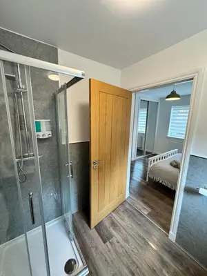 a bathroom with a shower and a wooden door at Inchconnachan Apartment in Bonhill