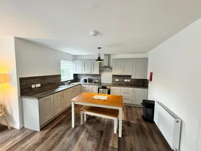 a kitchen with white cabinets and a wooden table at Inchconnachan Apartment in Bonhill