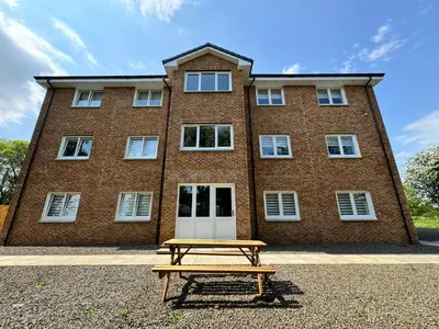 a picnic table in front of a brick building at Inchconnachan Apartment in Bonhill