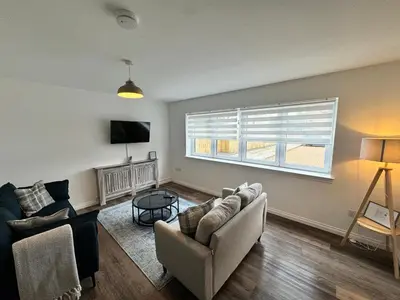 a living room with two couches and a tv at Inchconnachan Apartment in Bonhill