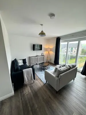 a living room with a couch and a chair and a tv at Inchchlonaig Apartment in Bonhill