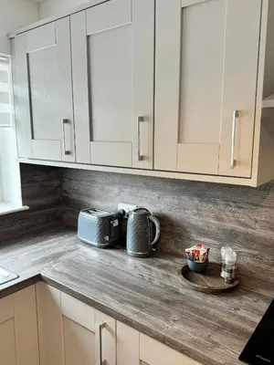 a kitchen with white cabinets and a toaster on a counter at Inchchlonaig Apartment in Bonhill