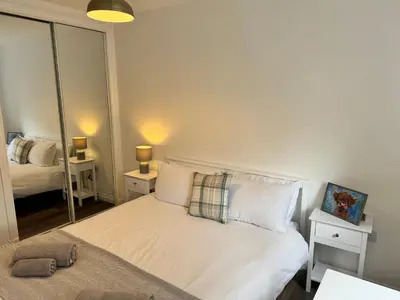 a bedroom with a white bed and a mirror at Inchchlonaig Apartment in Bonhill