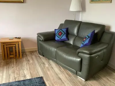 a green leather couch in a living room at Lednabra Cottage in Drymen