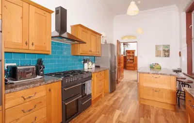a kitchen with wooden cabinets and a stove top oven at Garmoyle House & Garmoyle Mid Cottage in Dumbarton