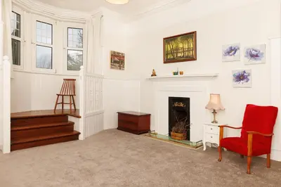 a living room with a fireplace and a red chair at Garmoyle House & Garmoyle Mid Cottage in Dumbarton