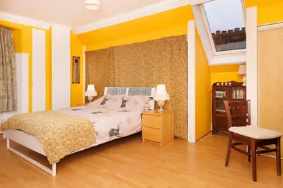 a bedroom with yellow walls and a bed and a chair at Garmoyle House & Garmoyle Mid Cottage in Dumbarton