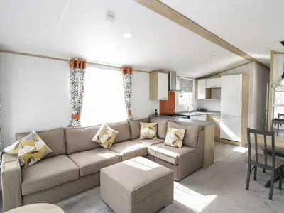 a living room with a couch and a kitchen at Ash in Denny