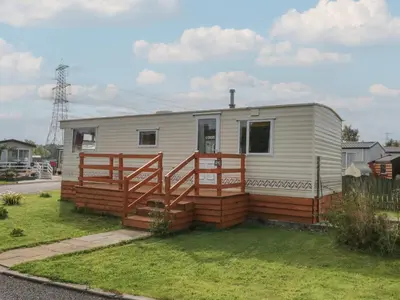 a small white caravan with a wooden deck at Holly in Denny