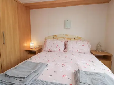 a bedroom with a bed with a pink comforter at Holly in Denny