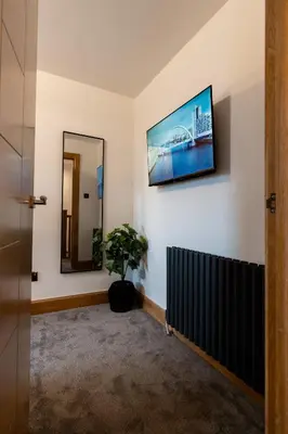 a hallway with a mirror and a potted plant at 24 Kingsford Court in Newton Mearns