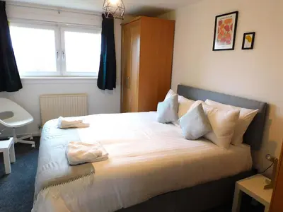 a bedroom with a bed with white sheets and a window at No 52 - Newly refurbished 3 bedroom home in East Kilbride in East Kilbride