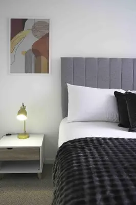 a bedroom with a bed and a side table with a lamp at Redding House in Falkirk