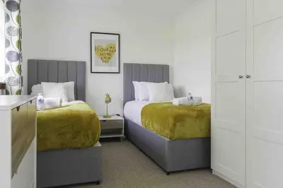 a bedroom with two beds with yellow sheets at Redding House in Falkirk