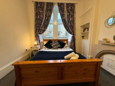 a bedroom with a large bed with a window at 2 Bed Flat - Street Parking in Glasgow