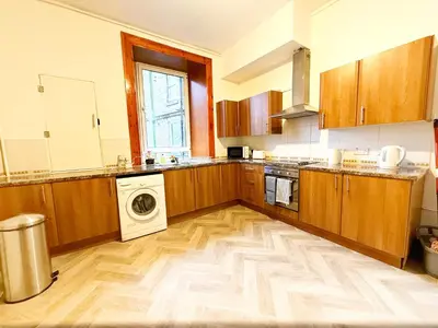 a kitchen with wooden cabinets and a washer and dryer at 2 Bed Flat - Street Parking in Glasgow