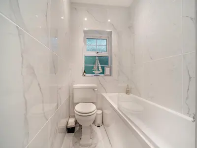 a white bathroom with a toilet and a bath tub at North Lodge in Colintraive