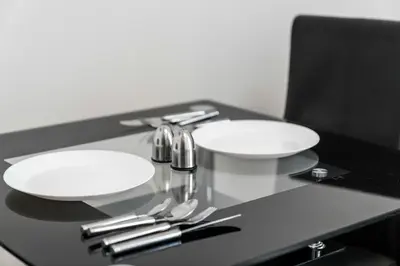 two white plates and utensils on a black table at Charming 1-Bedroom Home in Alexandria in Alexandria