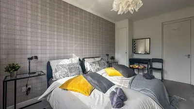 a bedroom with a bed with yellow and gray pillows at Brand New Scotland home 3rooms near Glasgow in Clydebank