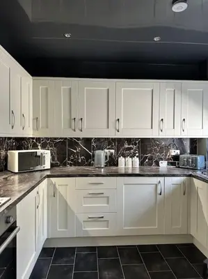 a kitchen with white cabinets and a black tile floor at 3 double bedroom spacious flat in Largs