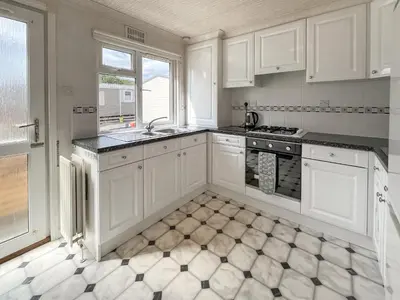 a kitchen with white cabinets and a tile floor at Tredegar in Newton Stewart