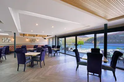 a restaurant with tables and chairs and a view of the water at Loch Earn leisure park in Saint Fillans