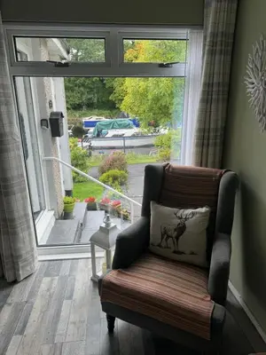 a living room with a chair and a large window at Loch Lomond Riverside Apartments B in Balloch