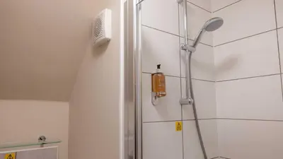 a shower in a white bathroom with a shower head at The Tarbet Hotel in Tarbet