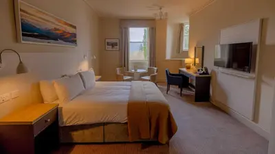 a bedroom with a bed and a desk and a television at The Tarbet Hotel in Tarbet