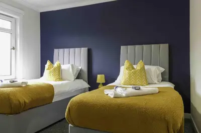 a bedroom with two beds with yellow and blue walls at Cochran House in Bathgate